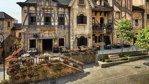 Un bâtiment historique sur lequel on peut lire l’inscription « MAISON DU ROI », et une cour intérieure aménagée avec des sièges en plein air.