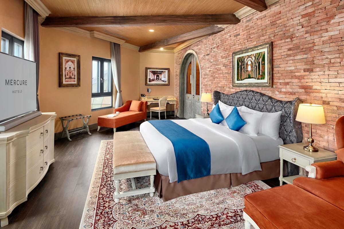 Een hotelkamer met een bed, een bureau, een stoel, een televisie en een bakstenen muur.