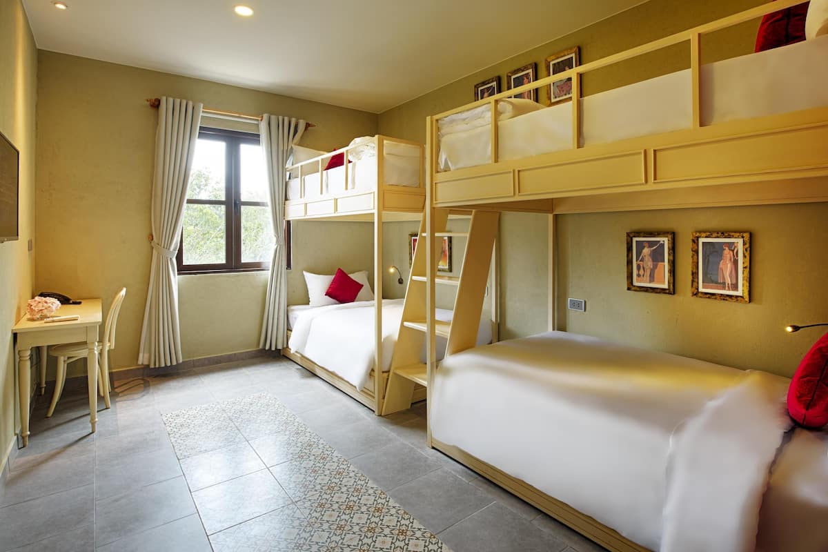 Een kamer met stapelbedden, een bureau, een stoel en een raam met gordijnen.