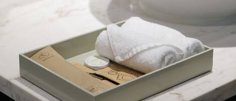 A bathroom with a marble countertop, a white towel, and a box containing toiletries.