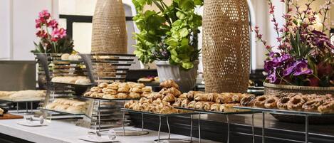 A buffet with various pastries and flowers.