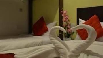 A hotel room with a bunk bed, a red bedspread, and a bouquet of flowers.
