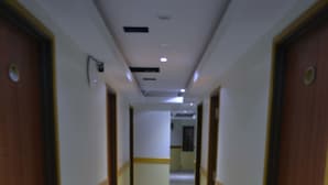 Un pasillo con puertas a ambos lados, suelo de baldosas e iluminación empotrada en el techo.