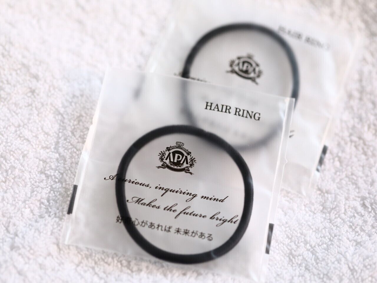 Two hair rings in clear plastic packaging with text.
