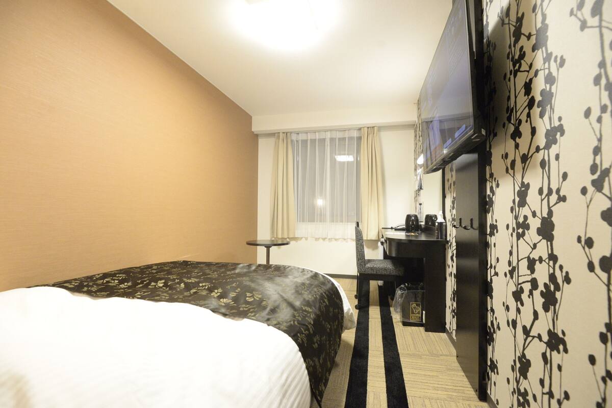 Una habitación de hotel con cama, escritorio, silla y televisor.