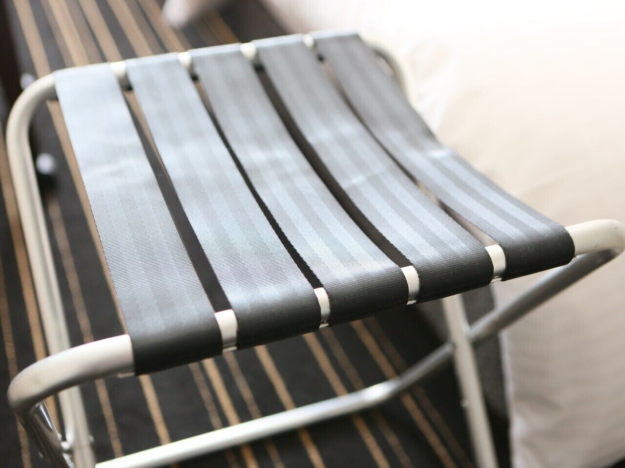 Una silla con estructura metálica y tela a rayas negras y blancas.