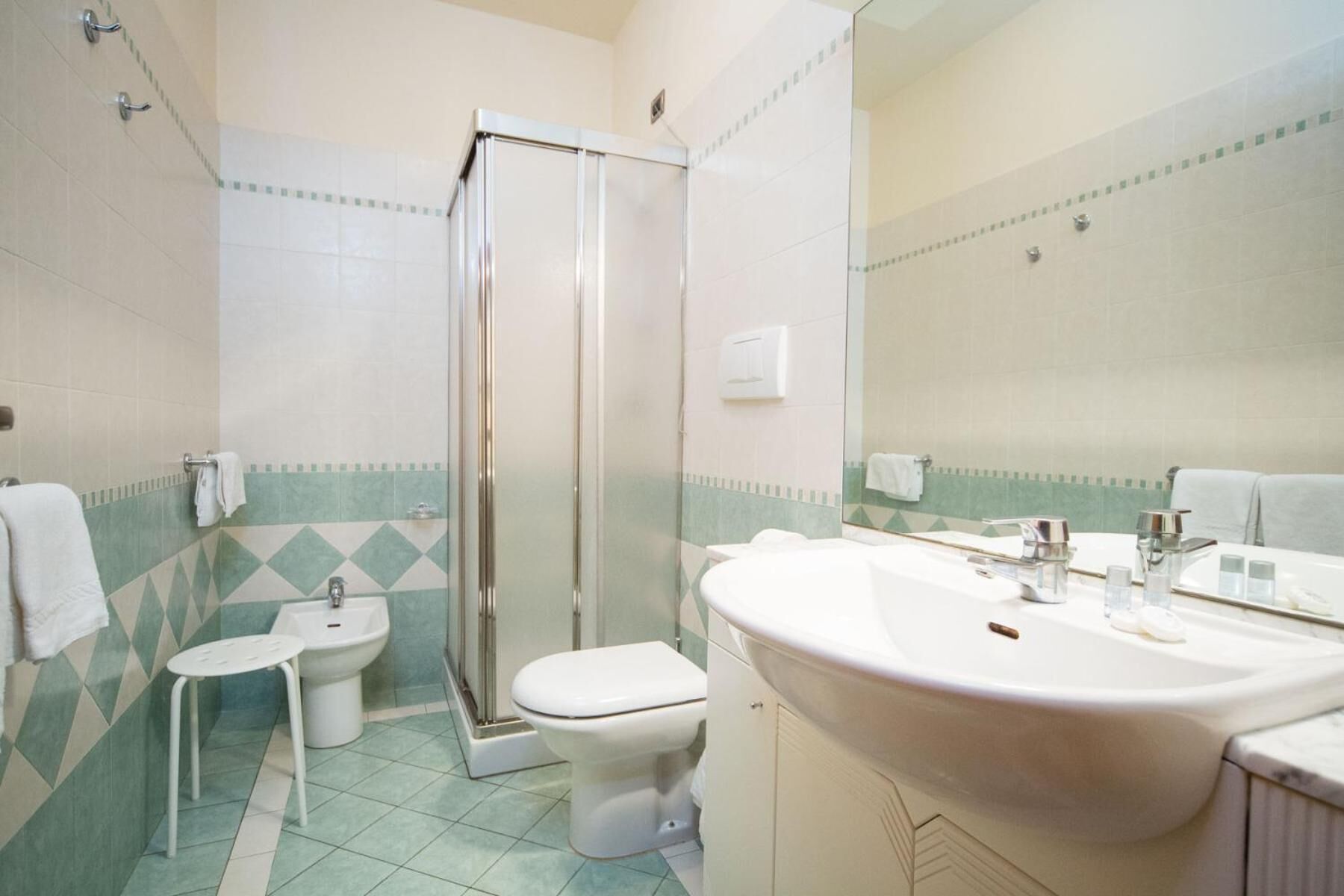 A bathroom with a shower, toilet, bidet, and sink.
