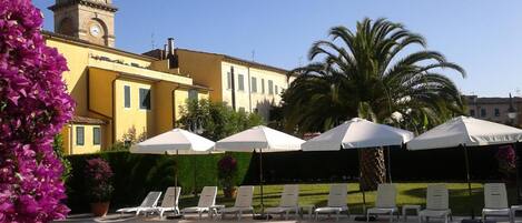 Alberca al aire libre, sombrillas en la alberca y camastros