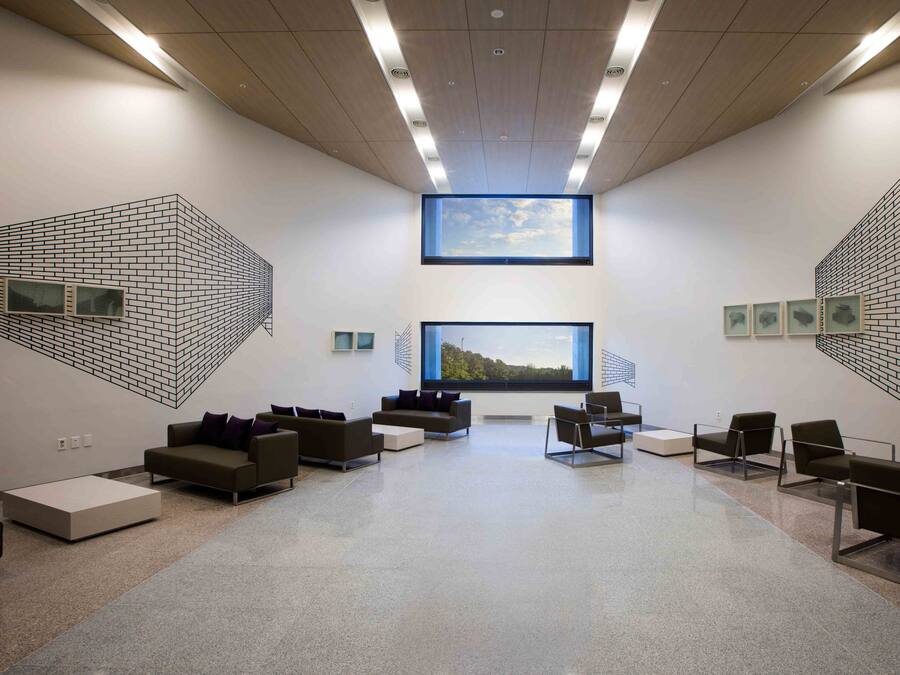 A modern waiting area with a large window, seating, and artwork on the walls.
