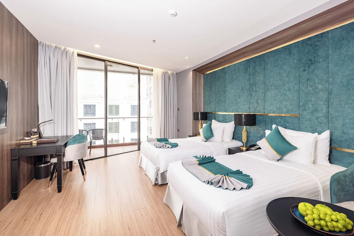 Een hotelkamer met twee bedden, een bureau, een stoel en een groot raam.