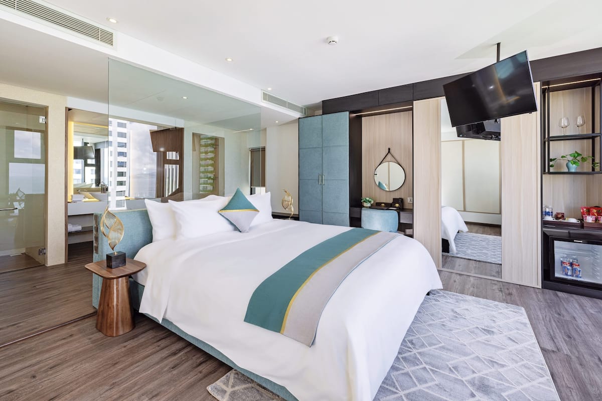 Een moderne hotelkamer met een groot bed, een televisie, een minibar en uitzicht op de stad.