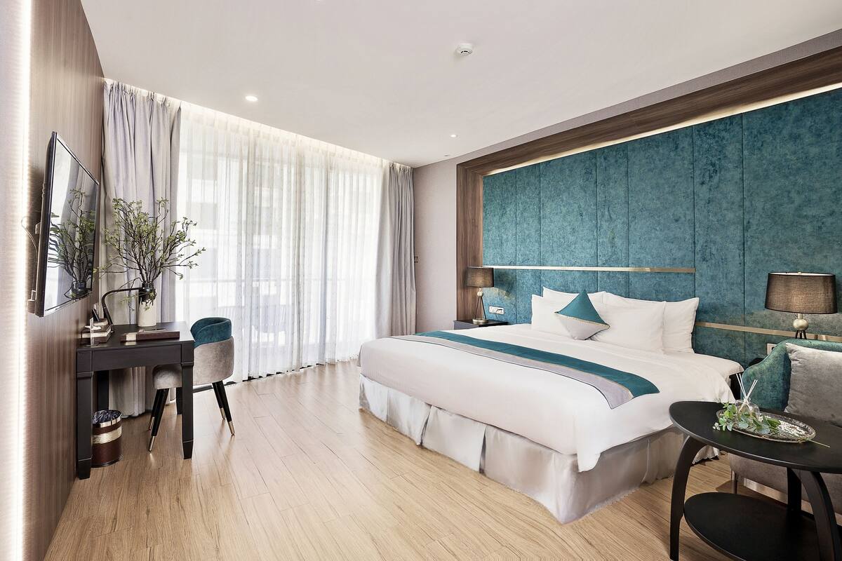Een moderne hotelkamer met een groot bed, een bureau, een stoel en een klein tafeltje.
