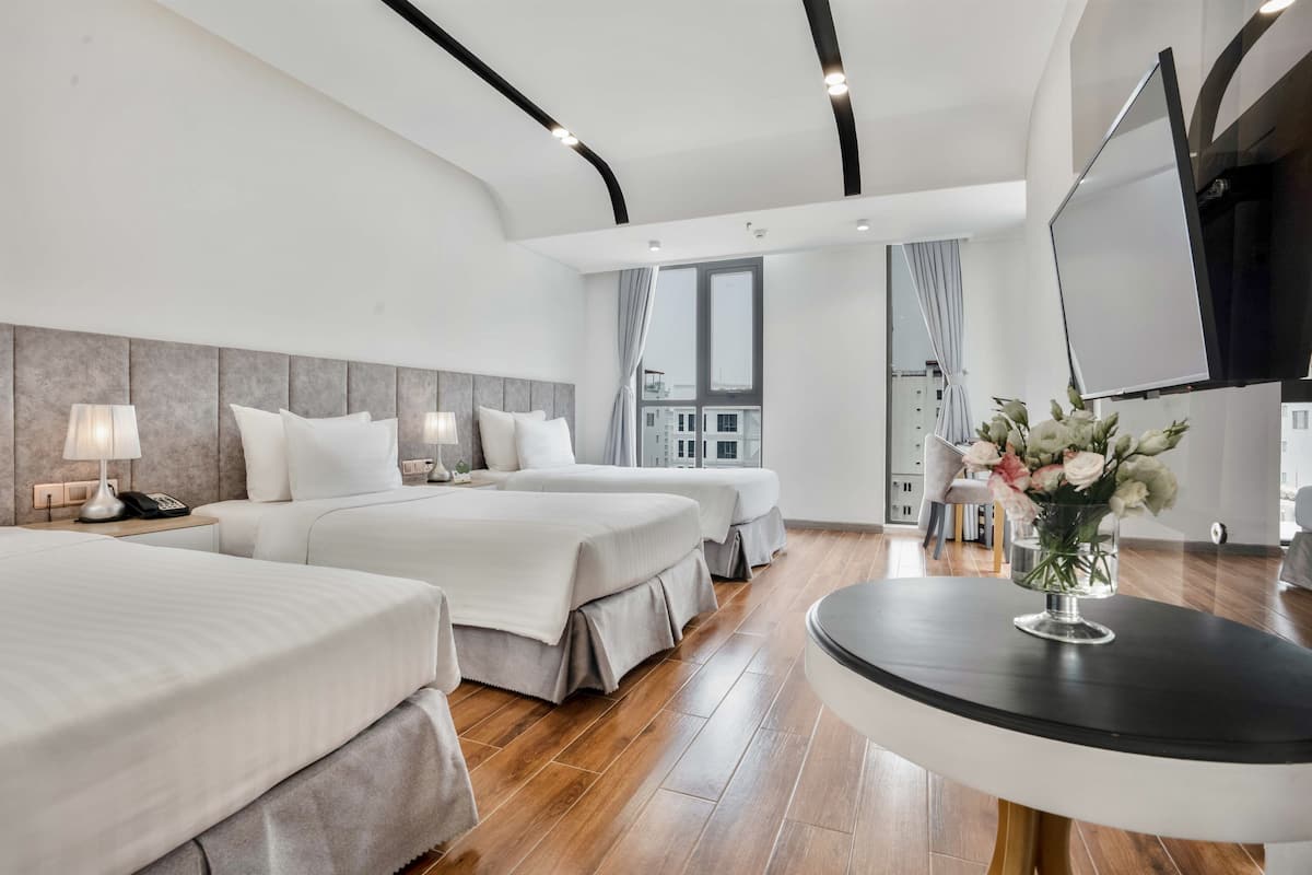 Een moderne hotelkamer met twee bedden, een televisie, een bureau en uitzicht op de stad.
