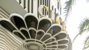 Um edifício moderno com um design arquitetônico singular, apresentando um grande logotipo estilizado em forma de 'C' e um teto decorativo.