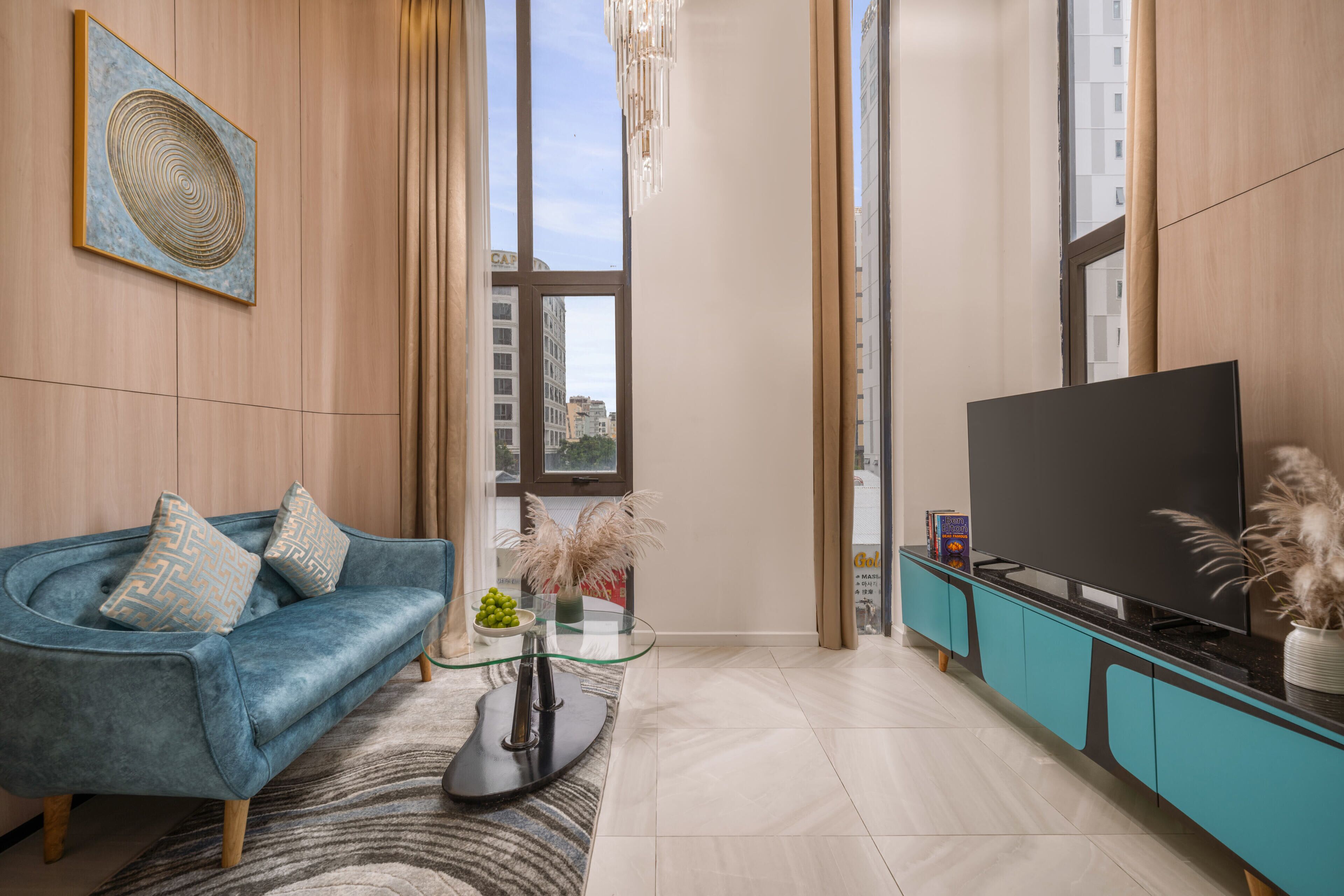Una sala de estar moderna con un sofá azul, una mesa de centro de vidrio, un televisor de pantalla plana y un mueble de entretenimiento color turquesa.