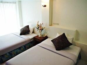 A hotel room with two beds, each with a zebra-patterned pillow and a vase of flowers on a nightstand. - Sukwilai Hotel (Hua Hin)