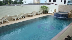 A swimming pool with clear water, surrounded by lounge chairs and a hot tub. - Sukwilai Hotel (Hua Hin)