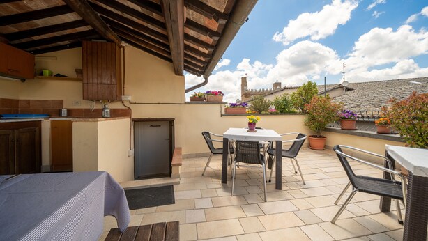 A patio area with a table and chairs, a small kitchen with a refrigerator, and potted plants. - Orvieto in Terrazza (Orvieto)