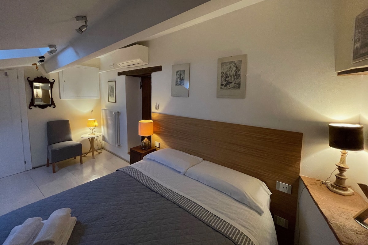 Una camera d'albergo con un letto, una sedia, una scrivania e una lampada.