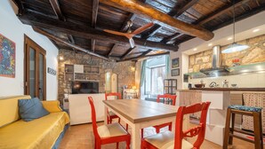A cozy kitchen with a wooden table and red chairs, a stone wall, and a wooden ceiling. - Orvieto in Terrazza (Orvieto)