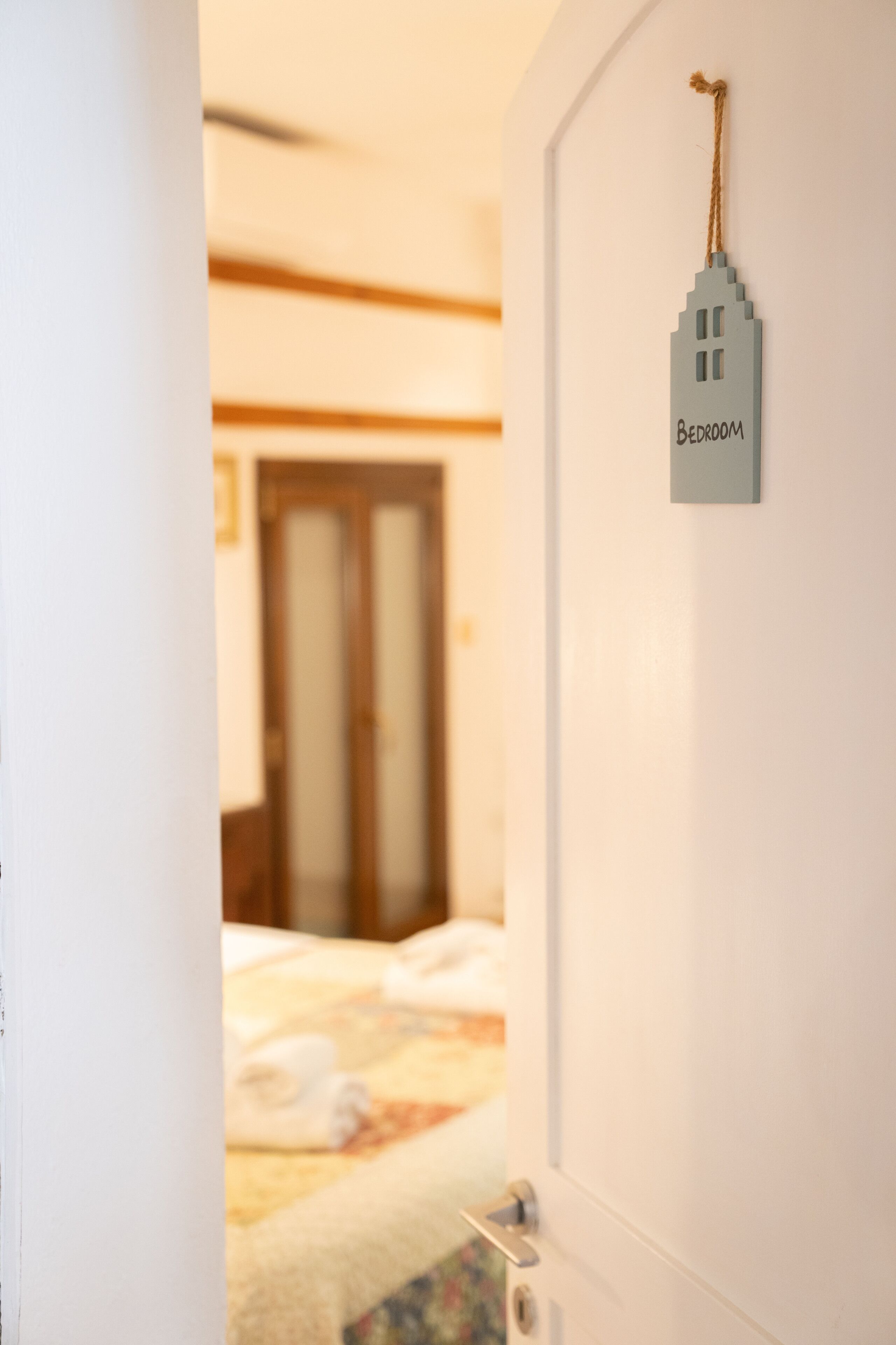 Ein Schlafzimmer mit einem Bett, einer Tür und einem an der Wand befestigten Schild, das den Raum kennzeichnet.