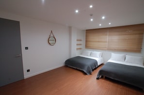 A modern bedroom with two beds, wooden flooring, and a large window with blinds. - YE'4 Guesthouse (Seoul)