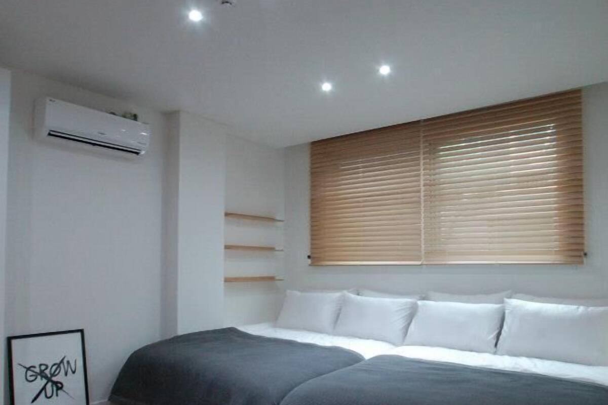 Une chambre moderne avec un grand lit, un plancher en bois, des étagères intégrées et une fenêtre avec des stores.