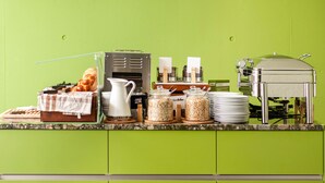 Montaje de un bufé de desayuno con diversos alimentos y una máquina de café.