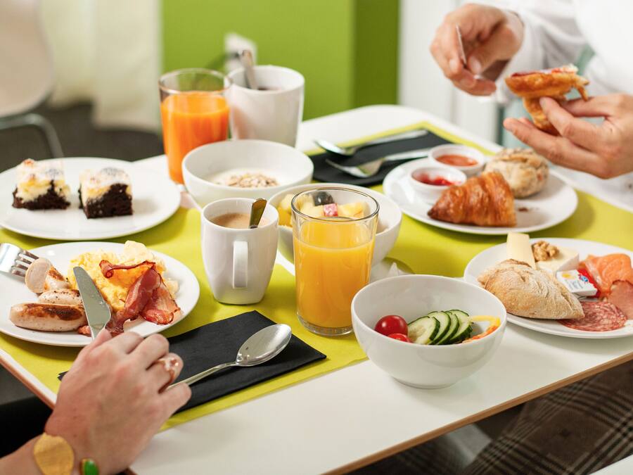 Ein Frühstückstisch mit verschiedenen Speisen, darunter Eier, Speck, Toast und Obst.