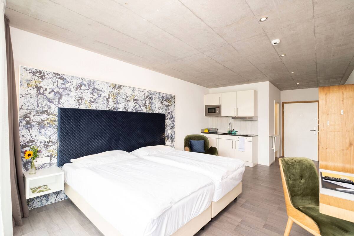 Una habitación de hotel moderna con una cama grande, un escritorio y una kitchenette.