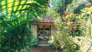 A small house with a tiled roof, a wooden porch, and a hammock. - Coconut Garden Resort (Gili Trawangan)