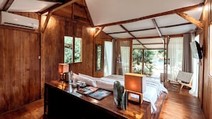 A wooden cabin with a bed, a desk, and a chair. There are windows and a view of the outdoors. - Coconut Garden Resort (Gili Trawangan)