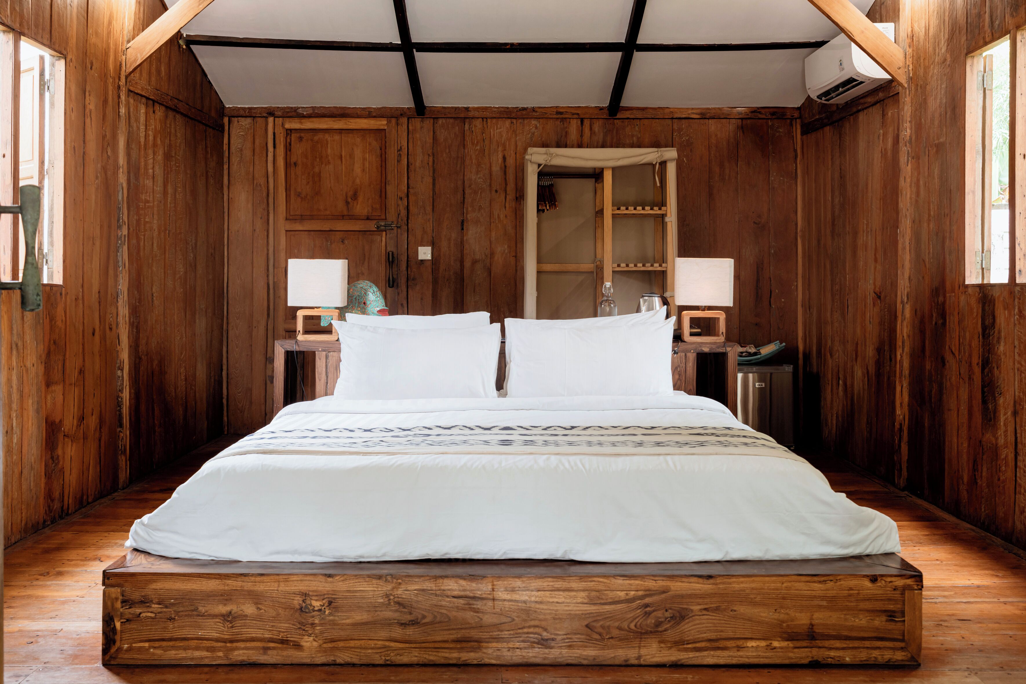 Ein Zimmer mit Holzboden, einem Bett, zwei Nachttischen und einem Fenster.