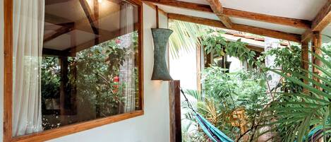 Un conjunto de mesa y sillas de madera en un patio con suelo de baldosas, una hamaca y plantas.