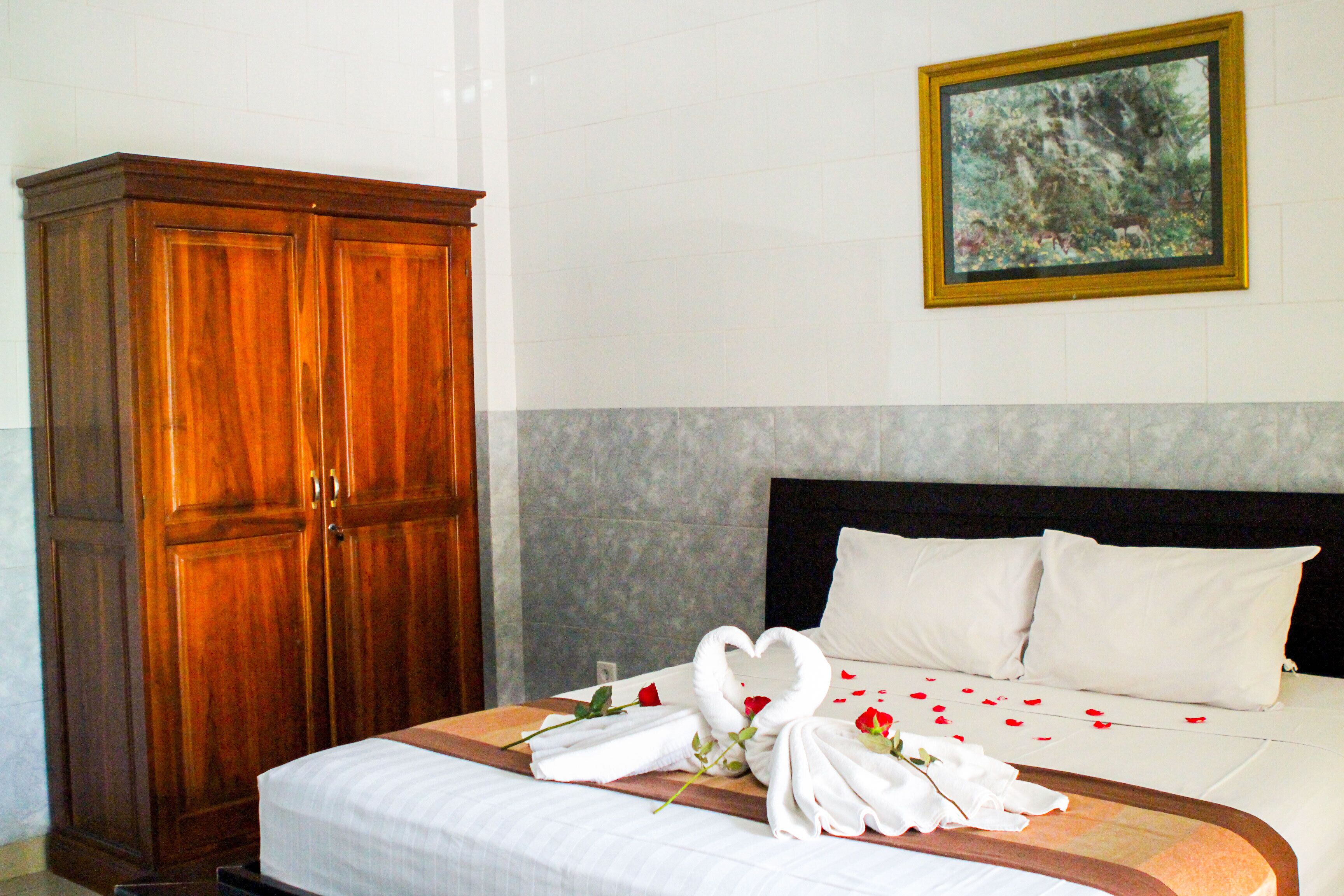Una habitación de hotel con una cama, un armario de madera y un cuadro en la pared.