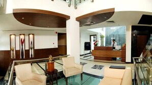 A hotel lobby with a reception desk, two armchairs, a sofa, and a decorative vase. - Silver Ark (Gurugram)