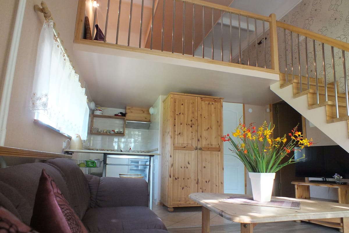 Ein Wohnzimmer mit einer Couch, einem Couchtisch und einer Treppe, die zu einer oberen Etage führt.