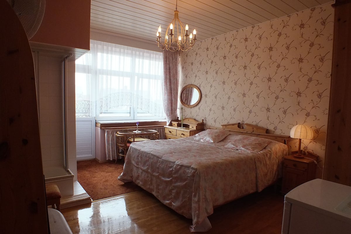 Ein Schlafzimmer mit einem großen Bett, einem Schminktisch, einem Frisierkommode und einer Chandelier.