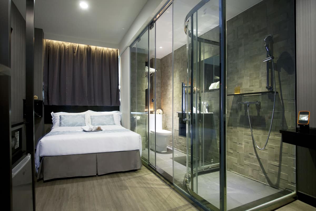 Een moderne hotelkamer met een groot bed, een douchecabine van glas en een apart toilet.