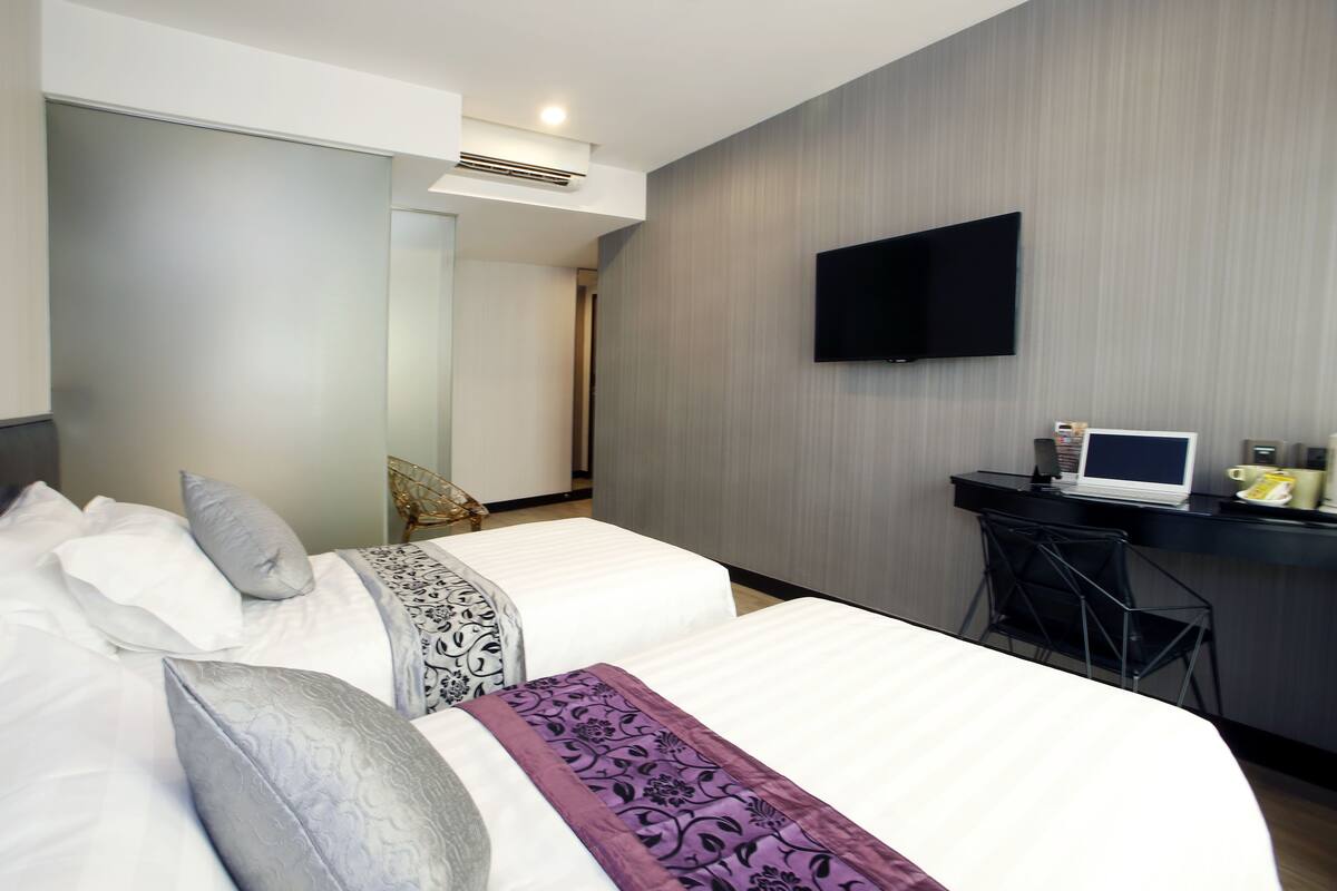 Een hotelkamer met twee bedden, een bureau met computer, een televisie en een stoel.