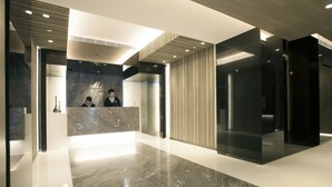 Un espace d’accueil moderne avec un comptoir de réception en marbre, un panneau en bois vertical et une cloison en verre.