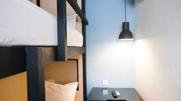 A bunk bed room with a desk and a hanging lamp.
