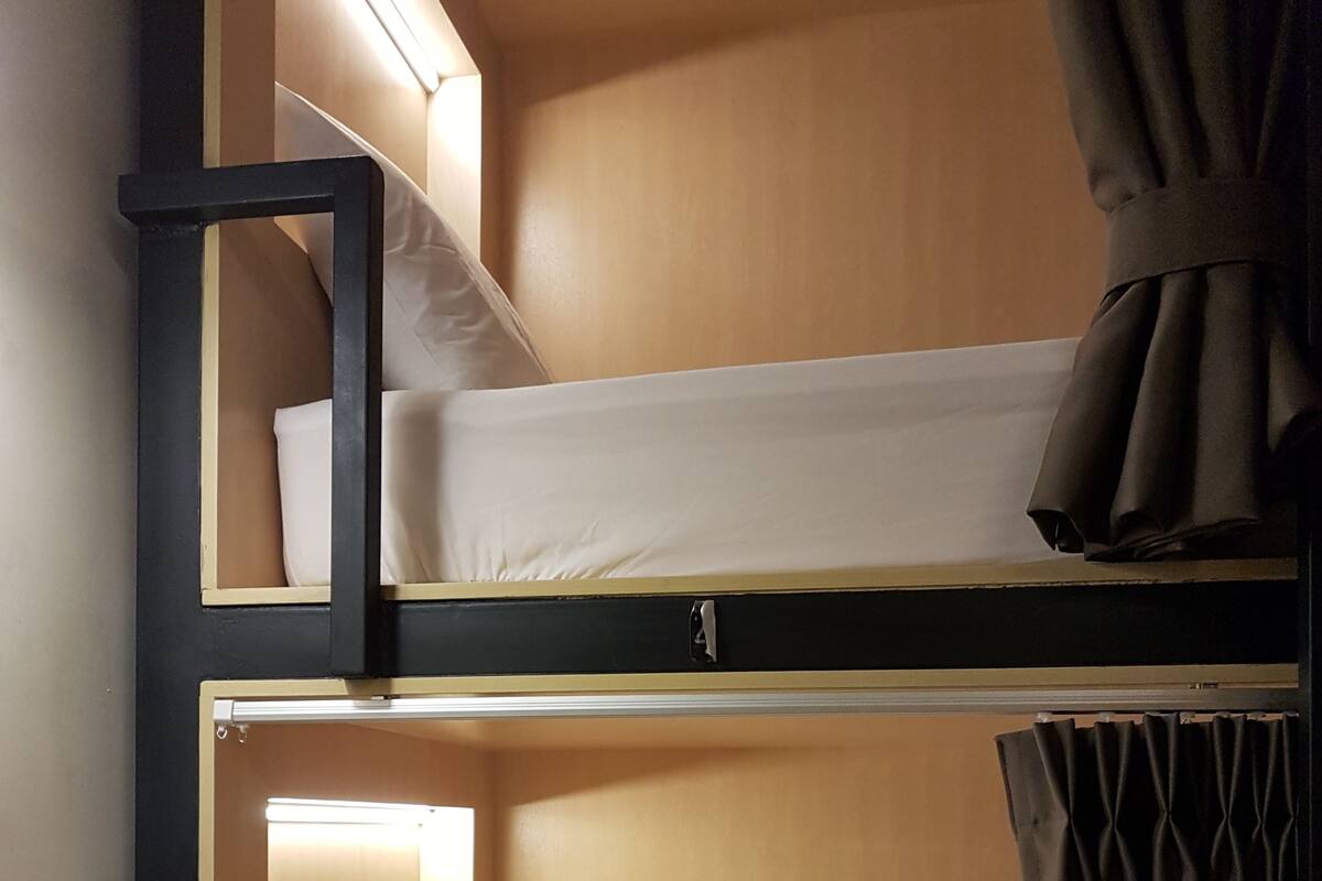 A bunk bed with a headboard, a pillow, and a curtain.