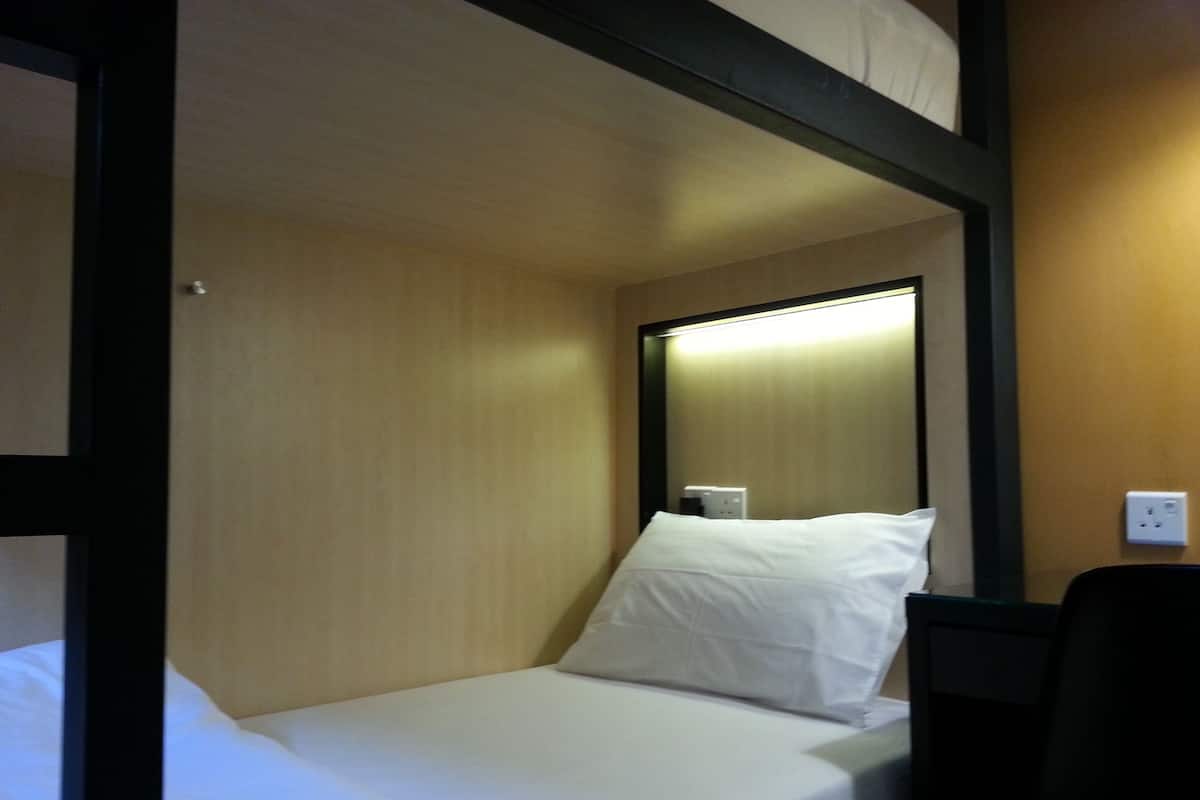 A single bed with white bedding in a room with wooden walls and a black frame.