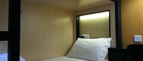 A single bed with white bedding in a room with wooden walls and a black frame.