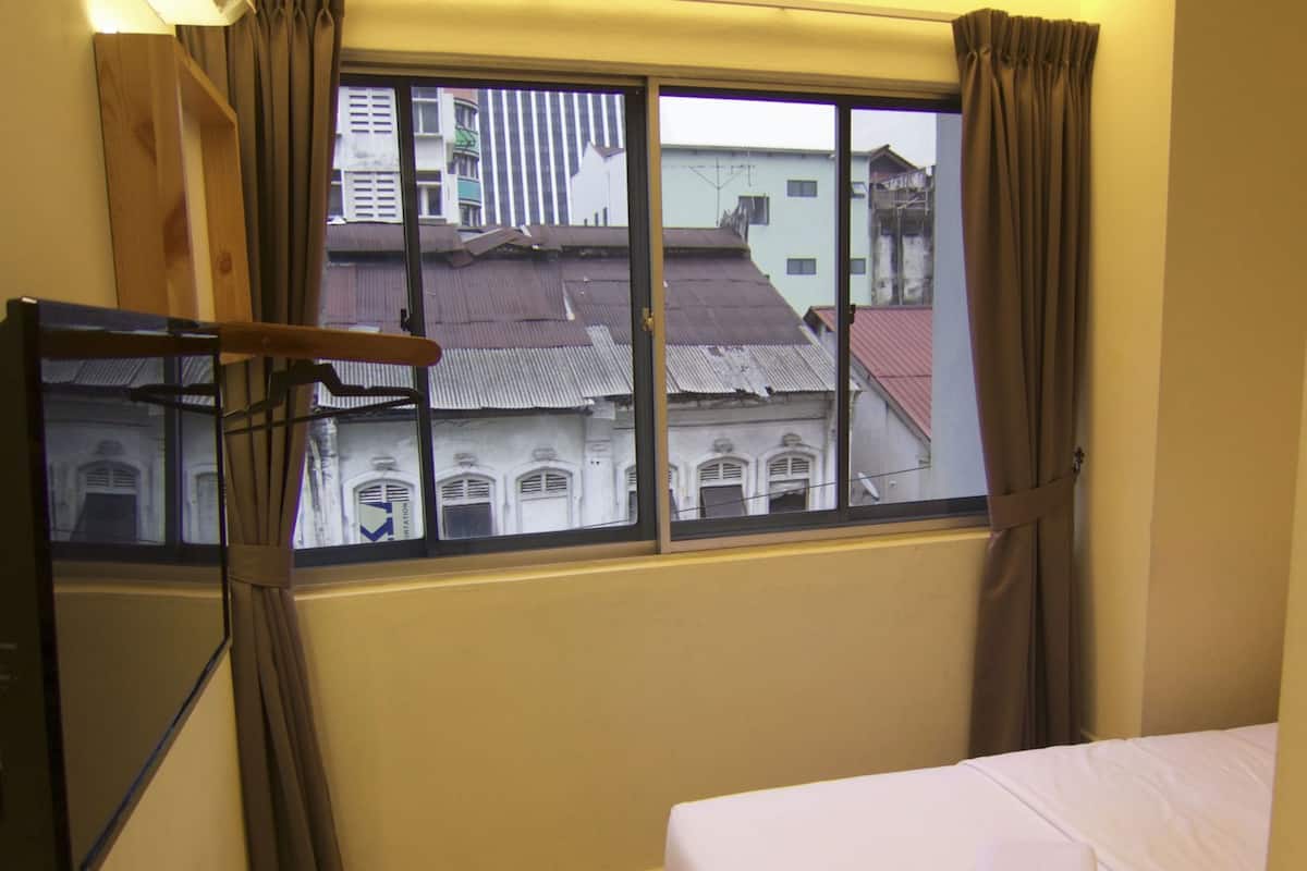 A hotel room with a bed, a TV, and a window with curtains.