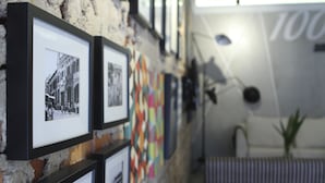 A wall with framed photographs and a colorful quilt. - 1000 Miles (Kuala Lumpur)