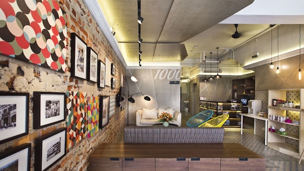 A modern interior with a brick wall, framed photos, a sofa, and a dining area. - 1000 Miles (Kuala Lumpur)