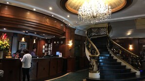 A lobby with a reception desk, a chandelier, and a grand staircase. - Citystate Tower Hotel (Manila)