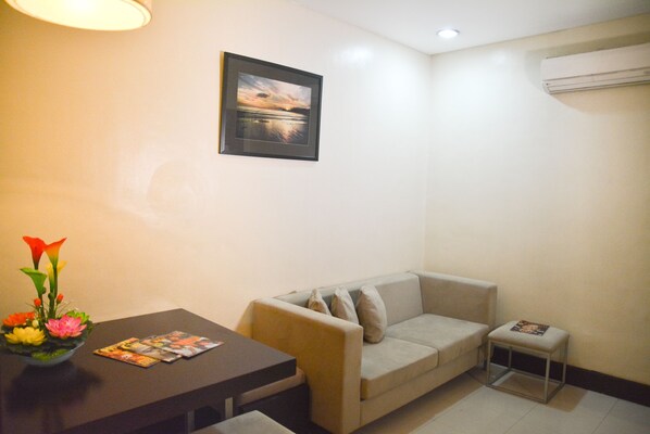 A living room with a sofa, a small table with a vase of flowers, and a framed picture on the wall.